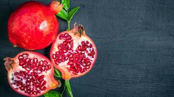 top view of Half ripe pomegranate and open red pomegranate with pomegranate leaves photo