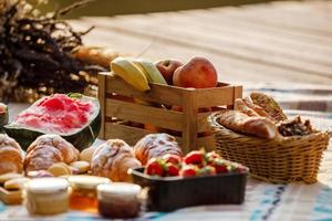 picnic en el parque. frutas frescas, refrescos helados y croissants en un caluroso día de verano. picnic. enfoque selectivo foto
