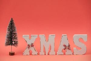 Wooden letters XMAS and decorative Christmas tree on pink background. Christmas greeting card photo