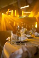 Empty glass set in restaurant. wedding, decor, celebration, holiday concept - romantic table setting with white tablecloth, plates, crystal glasses photo