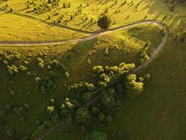 vista aérea de los hermosos cárpatos de montaña, ucrania a la luz del sol. drone filmó un paisaje con bosques de coníferas y hayas, alrededor de un sinuoso camino serpenteante, foto aérea de helicóptero