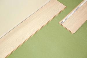 instalación de laminado o parquet en la habitación, trabajador instalando suelo laminado de madera, marcando la longitud del laminado. poner suelo laminado en casa. medir con una cinta métrica foto