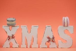 The wooden word xmas with colorful macaroons or macarons on pink background. Xmas decoration. New Year home decor photo