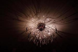 Chandelier.Home, beautiful chandelier.A luxurious lamp hangs from the ceiling. handelier with crystal.Chandelier ceiling lights, black background with copy space.Close Up. photo