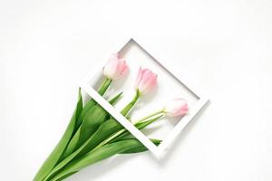 Flowers pink tulips in photo frame on white background. Wedding. Birthday. Happy woman's day. Mothers Day. Valentine's Day. Flowers composition romantic. Flat lay, top view, copy space