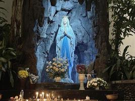 la cueva de la virgen maría, la estatua de la virgen maría en una iglesia católica de la capilla de la cueva de roca con vegetación tropical foto