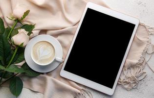 Top view a cup of coffee latte art heart shape with a pink rose and tablet photo