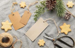 Blank gift tags with pine branch and Christmas cookies on textile background. The concept of preparing for the Christmas holiday photo