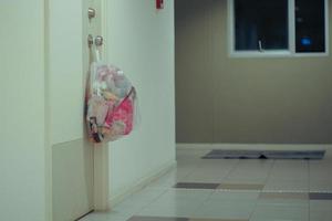 Waste in the plastic bag hanging on the door knob of the room at the apartment photo