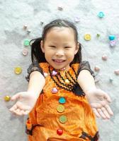 Portrait Asian little girl throwing and eating candy and chocolate from trick or treat photo