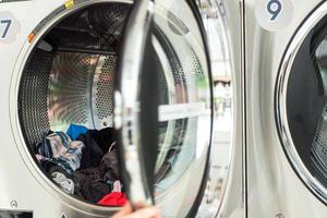 Selective focus on the pile of clothes inside the dry machine with blurred front door in foreground photo