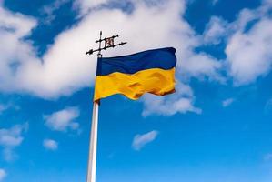 Yellow-blue national Ukrainian flag against the blue sky with clouds photo