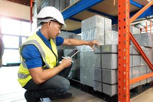 Happy Asian senior supervisor working - inspecting an items in the warehouse, smart and good looking handsome Asian man portrait while working in the warehouse. Warehouse worker working. photo