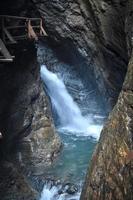 hermosa cascada en una cueva en un barranco llamado raggaschlucht con un puente de madera o una ruta de senderismo a la izquierda. naturaleza salvaje en austria. foto