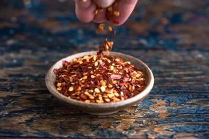 Sprinkling Red Pepper Flakes in a Bowl photo