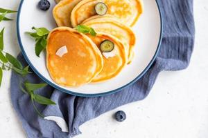 Traditional fluffy pancakes with orange jam, blueberries, coconut chips and mint for healthy breakfast, light background. High key photography. photo