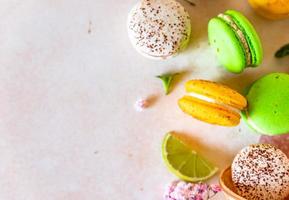 coloridos macarons franceses o italianos con lima, menta y flores, fondo de hormigón claro. fondo dulce de comida. foto