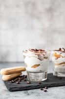 postre tradicional italiano tiramisú, fondo de piedra. Porción de postre con sabor a café a base de savoiardi y mascarpone decorado con cacao. foto