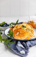 panqueques esponjosos tradicionales con mermelada de naranja, arándanos, chips de coco y menta para un desayuno saludable, fondo claro. fotografía de alta clave. foto