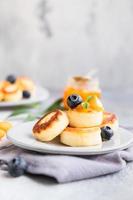 Cottage cheese pancakes, sweet curd fritters with blueberry and physalis, concrete background. Syrniki with jam and berries for a healthy breakfast. photo