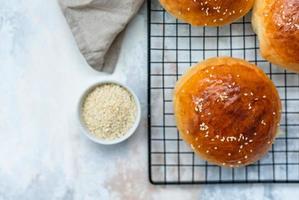 Round buns with sesame seeds, bread rolls. Tasty homemade burger bread with sesame, concrete background. Freshly baked hamburger buns. Top view. photo