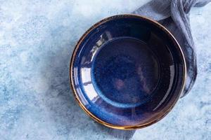 placa de mármol azul artesanal vacía y toalla de cocina, fondo de hormigón azul. plantilla de menú de exhibición de alimentos. vista superior. foto