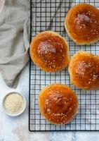 bollos redondos con semillas de sésamo, panecillos. sabroso pan casero de hamburguesa con sésamo, fondo de hormigón. bollos de hamburguesa recién horneados. vista superior. foto