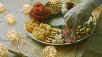 charcutaria plana com salame, diferentes tipos de queijo. tem frutas secas, nozes diversas e mel. arranjo de férias com velas acesas video