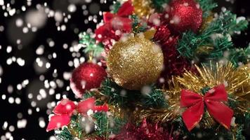 sneeuwen Aan Kerstmis versierd pijnboom boom, sneeuw vallend Bij langzaam beweging in winter, kerstballen dichtbij omhoog video