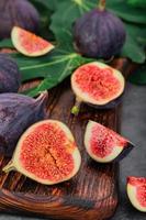 Figs cut into slices on a wooden cutting board close-up, selective focus. Vertical frame seasonal ripe fruits, mediterranean diet, idea for background photo