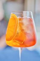 Aperol cocktail, closeup, selective focus. Aperol Spritz is a cocktail consisting of prosecco, aperitif and sparkling water. Beautiful orange cocktail vertical frame. photo