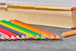 Colored pencils and old books on a light gray table, close-up, selective focus, blurred background. Back to school, education concept, layout template