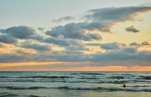 puesta de sol sobre el mar con nubes coloridas, luz solar naranja, puestas de sol de otoño, principios de otoño, temporada de terciopelo. la idea de un fondo o pantalla de bienvenida. foto