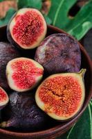 Juicy figs cut in half in an old clay plate, vertical frame. Selective focus close up. Seasonal ripe fruits, mediterranean diet photo