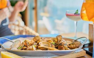 Blurred background with a dish of boiled vongole clams on a table in a cafe with copy space. Idea for splash screen or banner photo