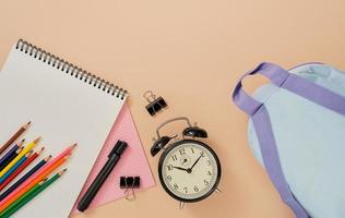 Back to school, school subjects, layout on a light flesh background. Notepad, backpack, pens, pencils, alarm clock, and other tools. Banner with place for text. photo