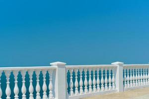 Summer view with classic white balustrade and empty terrace overlooking the mediterranean sea, vacation idea. Free space for text photo