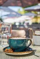 Vertical shot, a cup of espresso coffee, a glass of water and cookies on the table, coffee break time. Close-up, sunlight and selective focus, empty space, idea for advertising or banner photo