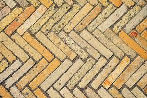 Pattern with rectangular yellow brick tiles in the form of a herringbone. Diagonal texture, abstract background of old brick ceramic cobblestone top view. Idea for easy desk wallpaper photo