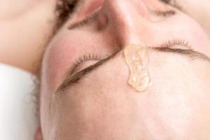 Liquid wax between the eyebrows of a young man photo