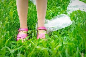 Plastic bags trash with children's feet on green grass photo