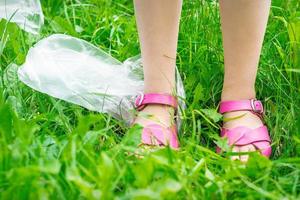 Plastic bags trash with children's feet on green grass photo