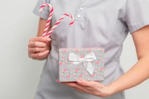 Female in medical uniform with gift box and christmas candy photo