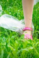 Plastic bags trash with children's feet on green grass photo