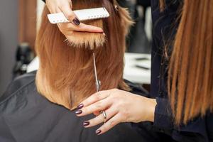 Hairdresser cuts red hair tips photo