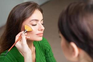 maquilladora aplicando maquillaje profesional de base tonal foto