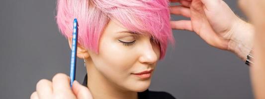 Hairdresser checking woman's pink hairstyle. photo