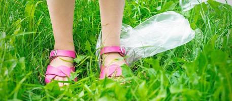 Plastic bags trash with children's feet on green grass photo