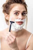 Woman shaving her face by razor photo