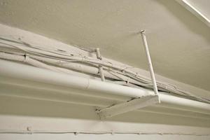 White water pipes and heating in the basement. Whitewashed pipes under the ceiling and wires in the house. Iron plumbing pipes in the house. photo